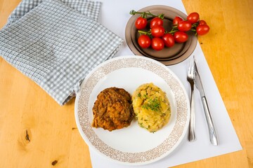 Fried fillet of chopped beef and mashed potato, twig of cherry tomato.