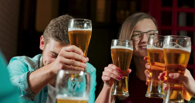 Group of happy friends having fun together, drinking beer and clinking their glasses, celebrating, happily smiling - friendship, recreational pursuit concept.