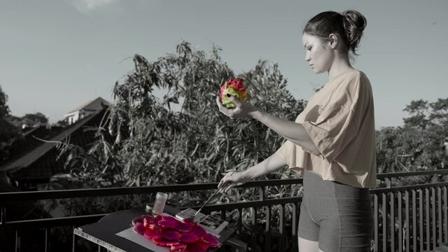 Black and white slow motion footage of woman painter holding a pink dragon fruit in one hand and a paint brush in the other. Crazy conceptual hyper realistic art performance outdoors. Modern artwork.