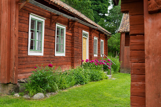 Idyllic Red Cottages In The Swedish Countryside With Green Meadows On A Beautiful Summer Day