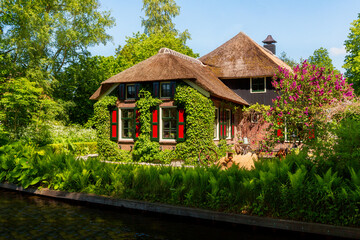 Fototapeta na wymiar Giethoorn, Netherlands, May 30, 2021. The famous village of Giethoorn in the Netherlands with traditional dutch houses, gardens and water canals and wooden bridges is know as 