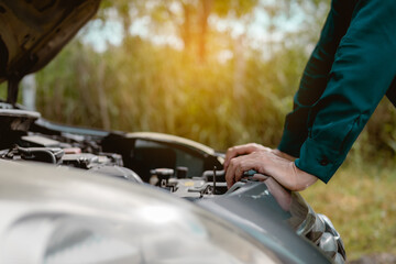 Close up hand man open car hood for repair as maintenance service. Man trying to check a car engine, looking inside open bonnet