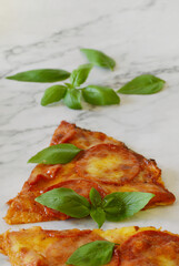 Small separated pepperoni pizza slices with fresh basil leaves on top.