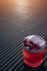 clover club cocktail drink with raspberry and rose petal outdoor at sunset