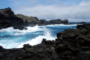 Fototapeta na wymiar Waves Crashing Against Black Lava Rock in Hawaii
