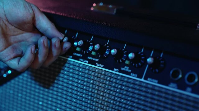 Musician Hand Turns The Volume Knob On The Guitar Amplifier