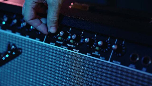 Musician Hand Turns The Volume Knob On The Guitar Amplifier