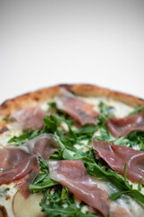 closeup of italian pizza with prosciutto, arugula and cheese on white background