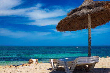 . A view of the Mediterranean coast with birch water on which a sun lounger and an umbrella are located.