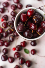 Sweet cherries in a tea mug on pink colored background, top view