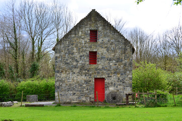 Fototapeta na wymiar Red Door on a Old Stone Barn in Ireland