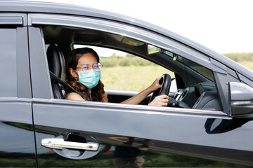 Young woman in casual protective medical mask driving in a car, protective mask against coronavirus, driver on a city street during a coronavirus outbreak. Safety during a pandemic, epidemic covid-19.
