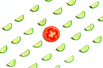 repeating pattern of sliced semicircles of fresh raw vegetable cucumbers for salad and a slice of tomato in the center isolated on a white background flat lay, top view