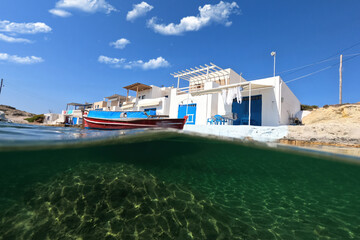 Underwater split photo of famous traditional fisherman settlement of Agios Konstantinos with colourful boat houses called sirmata, Milos island, Cyclades, Greece