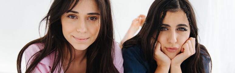 Naklejka premium positive armenian woman looking at camera near bored friend on white background, banner