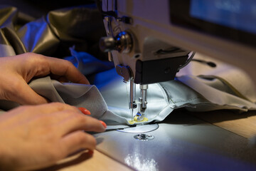 Female seamstress hand working on sewing machine, sew clothes, closeup shot. Woman fashion collection designer create new garment. Tailoring hobby or professional occupation concept, Small business
