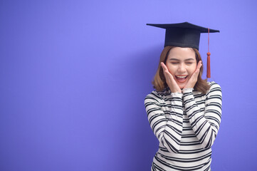 Portrait of young woman graduated over blue background