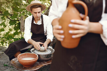 People making a vaze from a clay on a pottery's machine