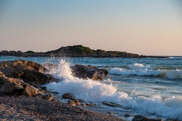 Sunset beach ocean wave splash. stone coast