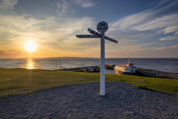 The sun setting behind the iconic signpost at John O'Groats in the Scottish Highlands, UK © Rob