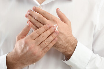 Man applying moisturizing cream onto hand, closeup