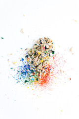 Shavings after sharpening of colored pencils lie in a heap on a white background. View from above