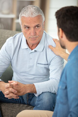man touching older man on the shoulder to console him