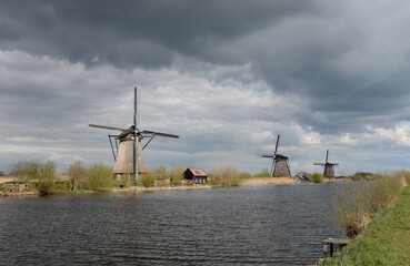 Typically Dutch polder landscape with windmills and cloudy skies