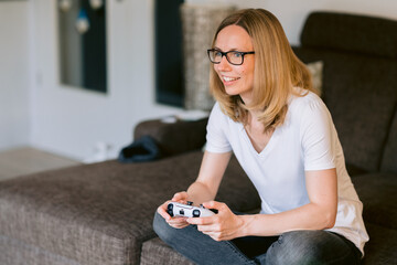 Frau spielt Playstation zu Hause auf dem Sofa und lächelt