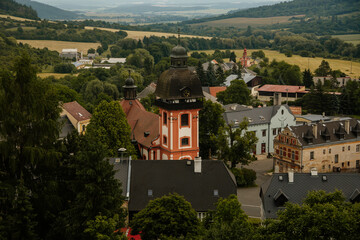 Fototapeta na wymiar Valec, Western Bohemia, Czech Republic, 19 June 2021: Church of the Nativity of St. John the Baptist with prismatic tower with shingle roof in center of old town at summer day