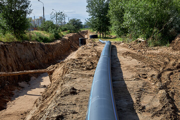 Plastic water pipe lies next to the trench for installation.Civil engineering