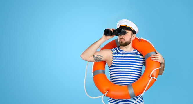 Sailor with binoculars and ring buoy on light blue background