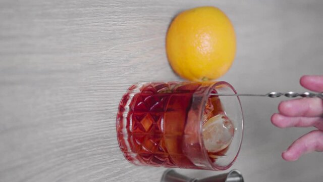 Slow motion of a negroni cocktail being stirred with a mixing spoon