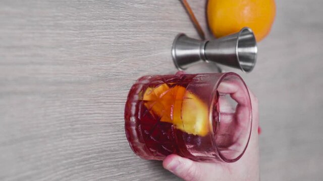 Slow motion of a glass of negroni cocktail being placed on top of a wooden table