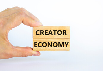 Creator economy symbol. Wooden blocks with words Creator economy on beautiful white background, copy space. Businessman hand. Business and creator economy concept.