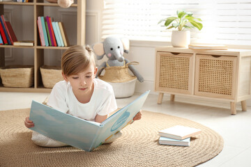 Little boy reading book on floor at home