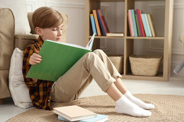 Little boy reading book on floor at home