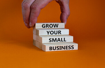 Grow your small business symbol. Concept words 'Grow your small business' on wooden blocks on a beautiful orange background. Businessman hand. Business, motivational and success concept.