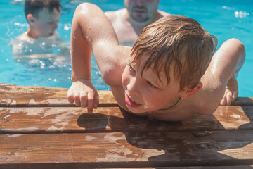 A wet boy gets out of the pool water after swimming on a hot summer day