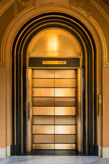 Closed golden elevator doors under arch in art deco style