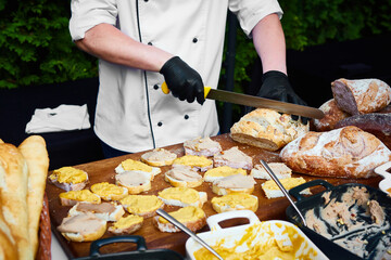 Mid-section of waiter chopping bread roll on chopping board on outdoor event