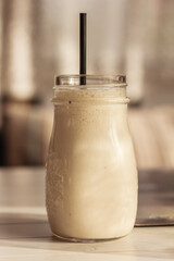 Close up of milk shake, smoothie, in the glass mud or bottle with a straw on white wooden table in the light background. Delicious dessert concept