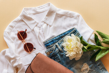 Feminine summer fashion flat lay with blouse, handbag, sunglasses and white peony flower on beige...