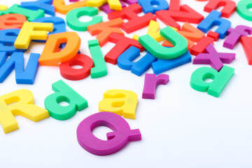Many colorful magnetic letters on white background, closeup