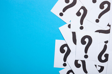 Frame made of notes with question marks on blue background. Pile of question marks, top view with...