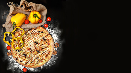 Italian melted cheese pizza on a black table with kitchen wood utensils and food ingredients: flour, cherry tomatoes, yellow bell peppers, garlic, walnuts and rosemary. Copyspace,flat lay,horizontal