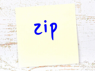 Yellow sticky note on wooden wall with handwritten word zip - obrazy, fototapety, plakaty