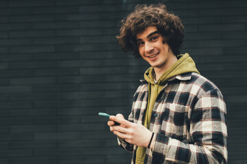 Smiling young man with cellphone standing outdoors