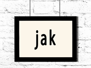 Black frame hanging on white brick wall with inscription jak © iushakovsky