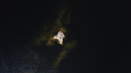 A girl sunbathes on a stone island in the middle of a lake in Karelia, Russia.